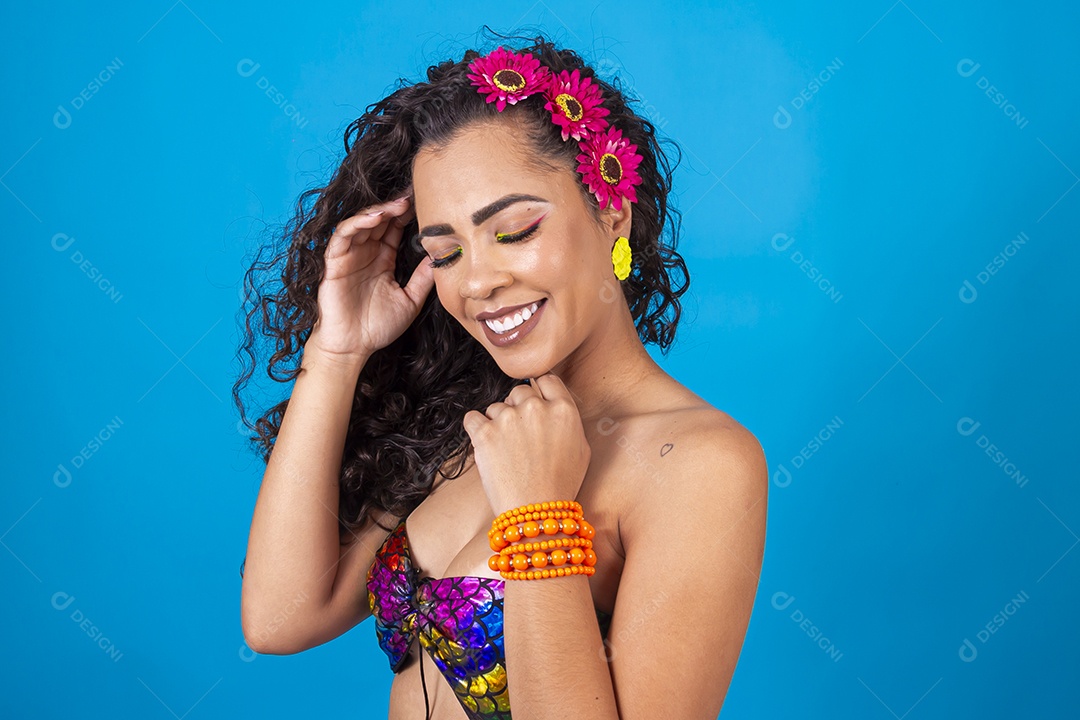 Linda mulher de cabelo cacheado com acessórios de flores no cabelo sobre fundo isolado azul.