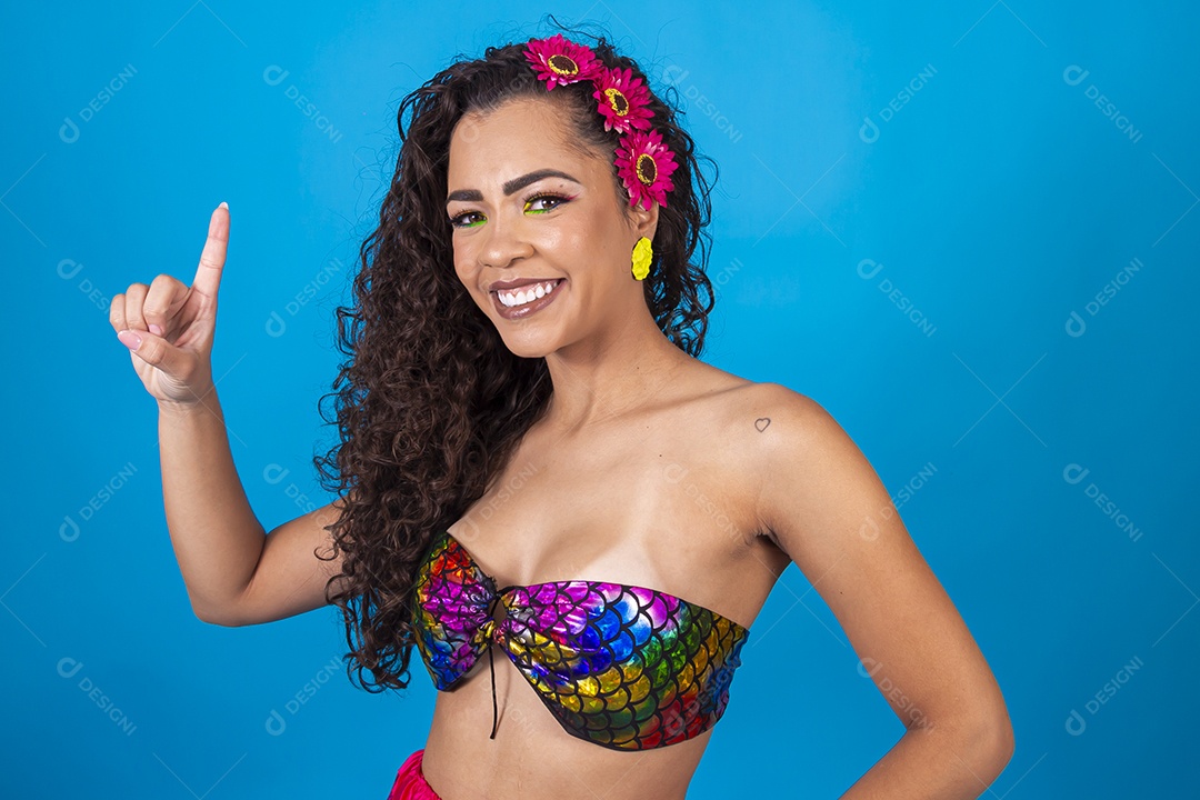 Linda mulher de cabelo cacheado com acessórios de flores no cabelo sobre fundo isolado azul.