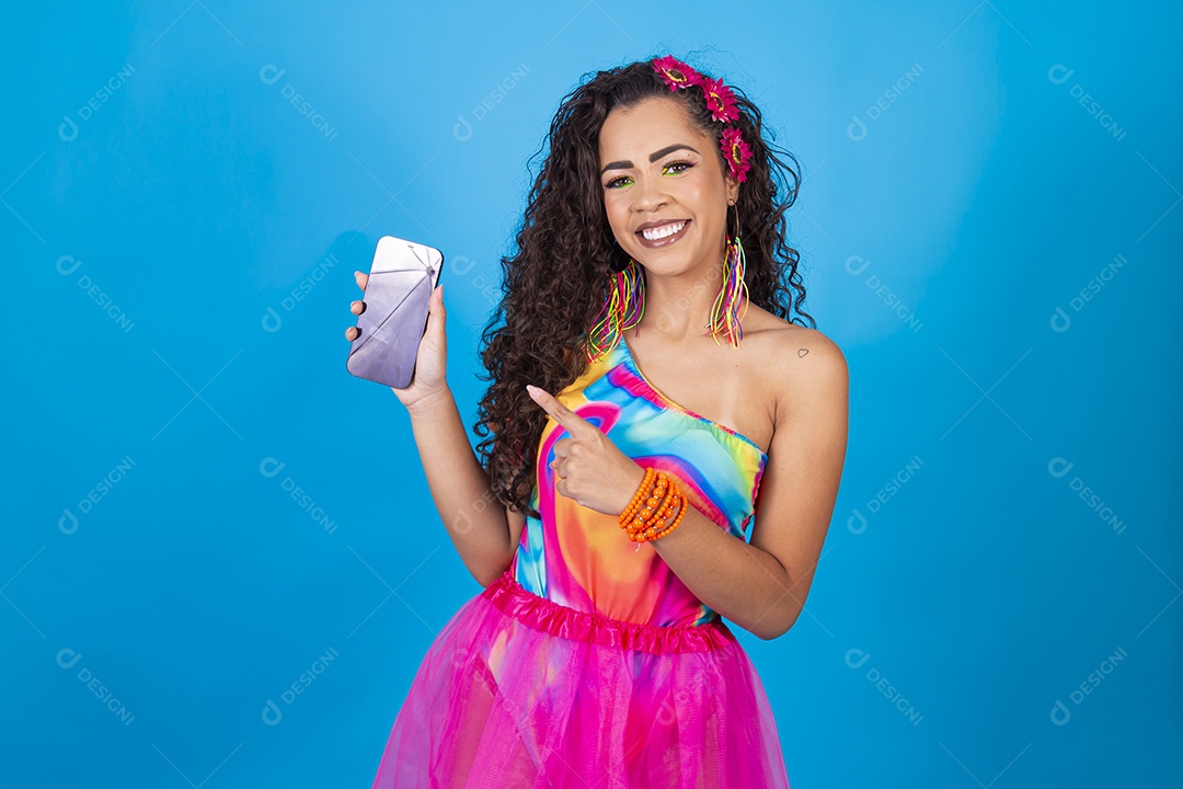Mulher de cabelo cacheado com fantasia de carnaval apontando para o celular.