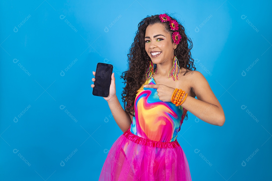 Mulher de cabelo cacheado com fantasia de carnaval apontando para o celular.