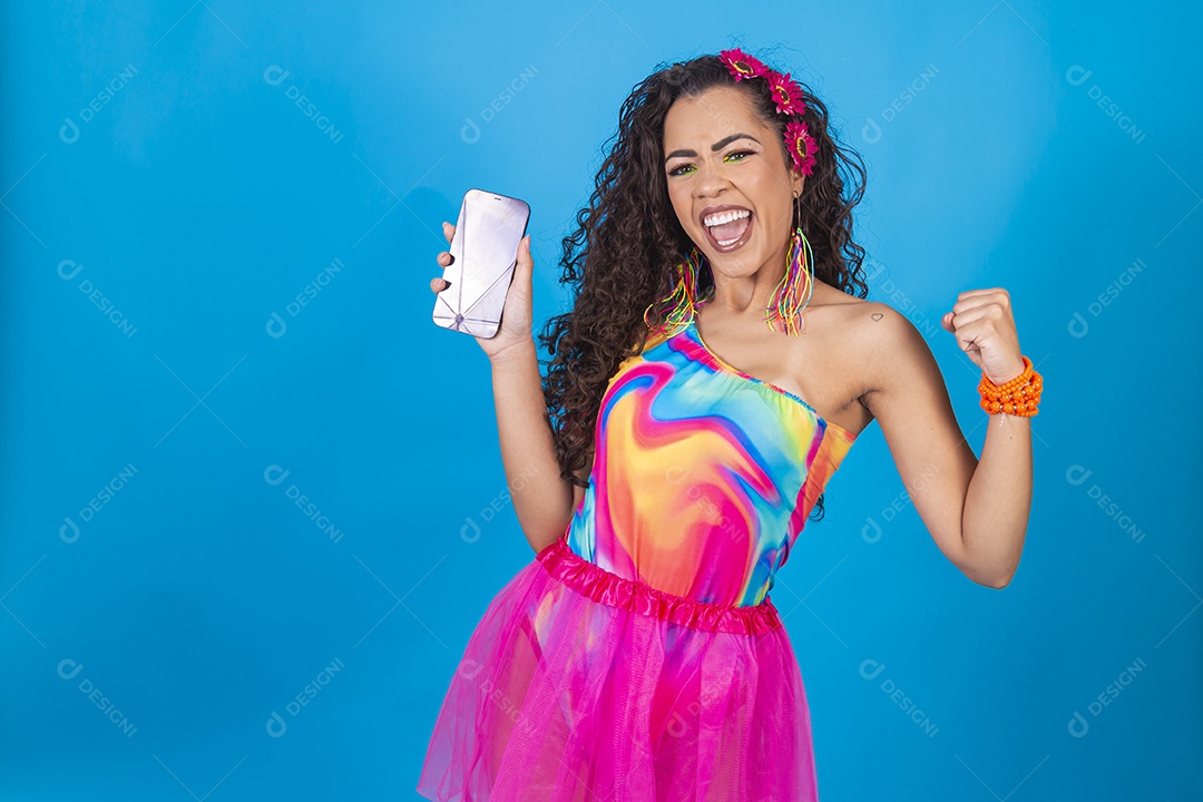 Mulher de cabelo cacheado com fantasia de carnaval segurando celular.