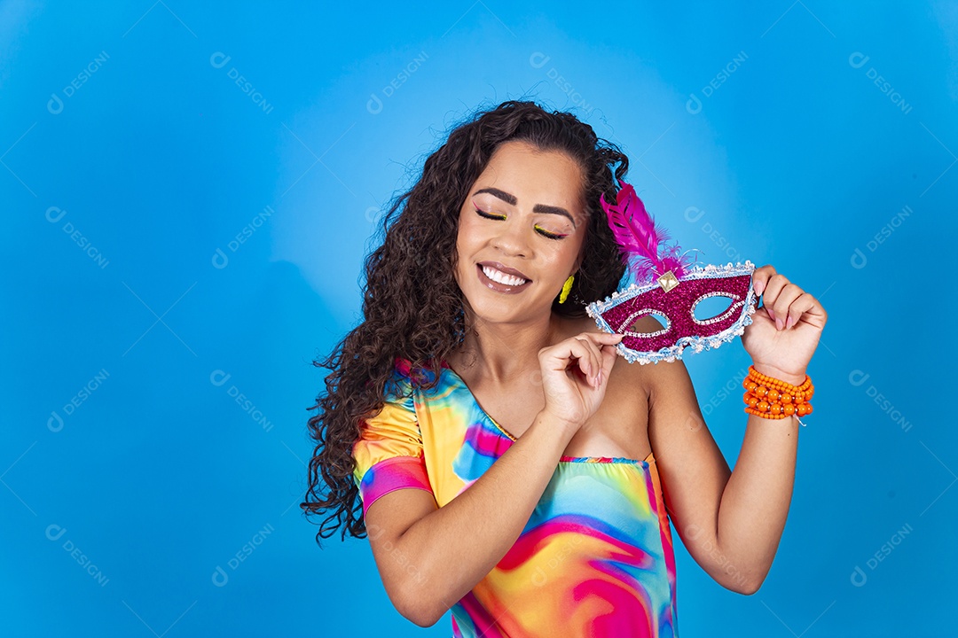 Linda mulher cabelo cacheado segurando máscara carnavalesca.