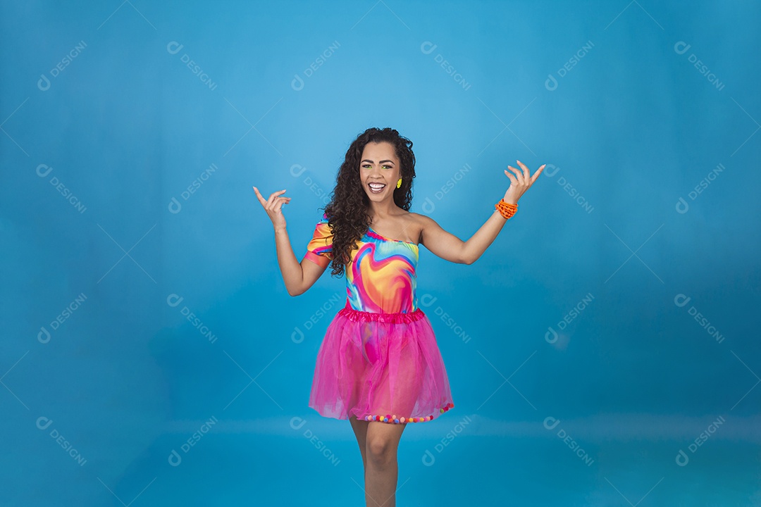 Linda mulher cabelo cacheado vestida com fantasia de carnaval sobre um fundo isolado azul.