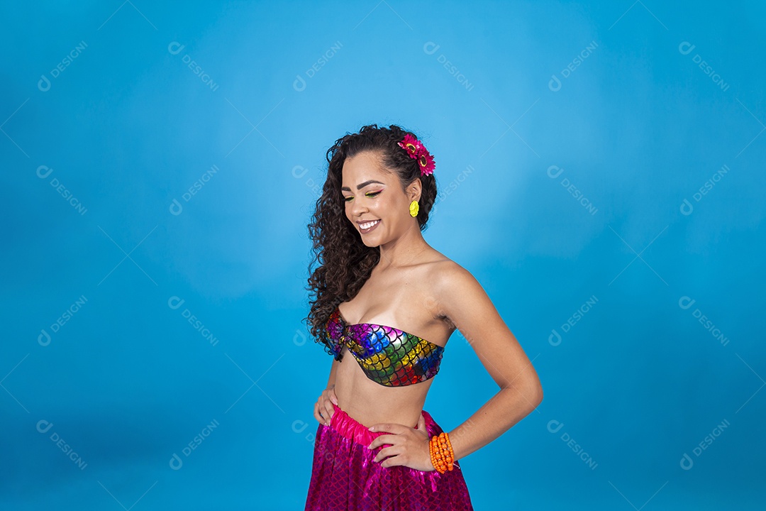 Linda mulher cabelo cacheado vestida com fantasia de carnaval sobre um fundo isolado azul.