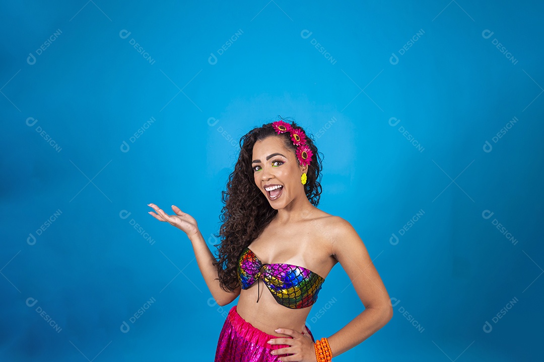 Linda mulher cabelo cacheado vestida com fantasia de carnaval sobre um fundo isolado azul.