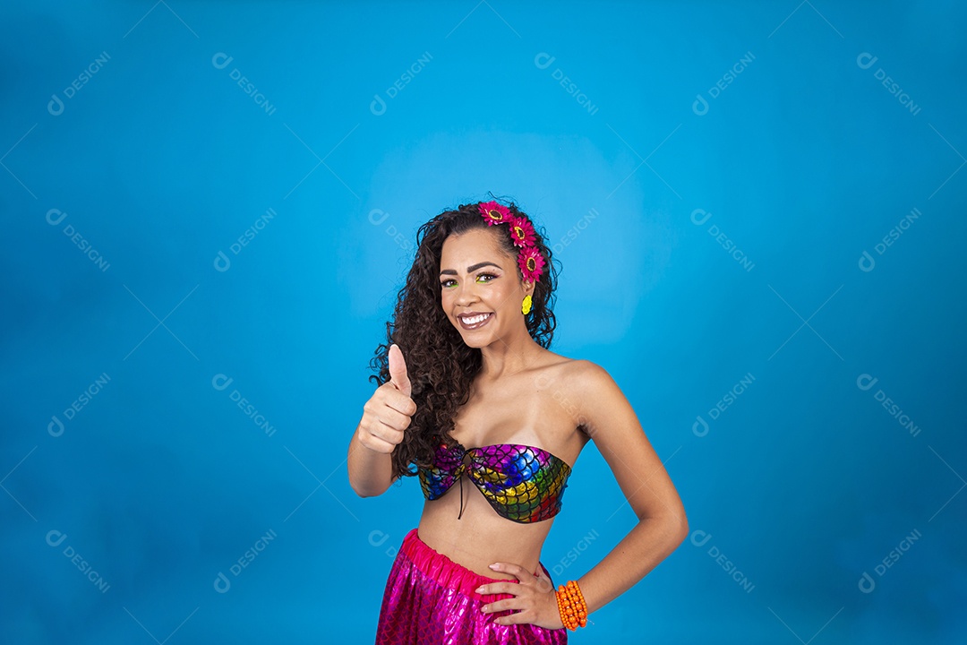 Linda mulher cabelo cacheado vestida com fantasia de carnaval sobre um fundo isolado azul.