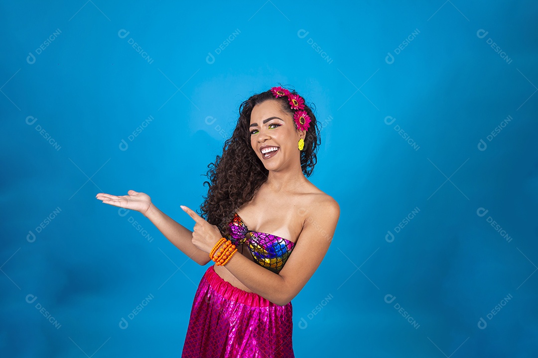 Linda mulher cabelo cacheado vestida com fantasia de carnaval sobre um fundo isolado azul.