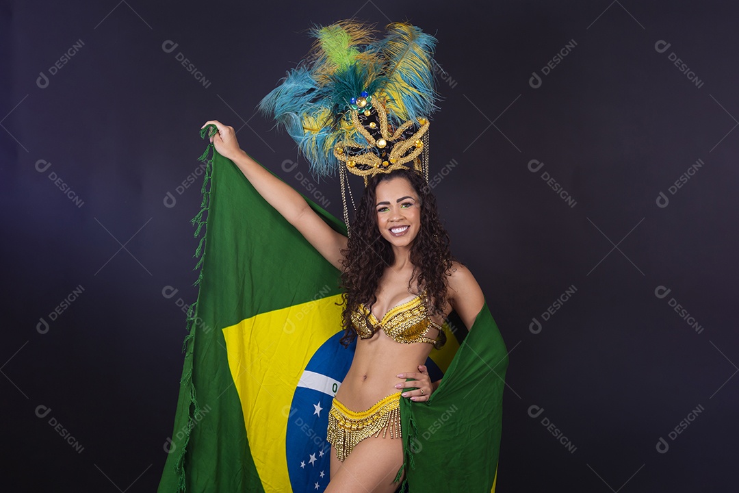 Linda passista fantasiada para o carnaval segurando bandeira do Brasil.