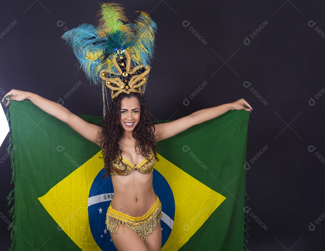 Linda passista fantasiada para o carnaval segurando bandeira do Brasil.