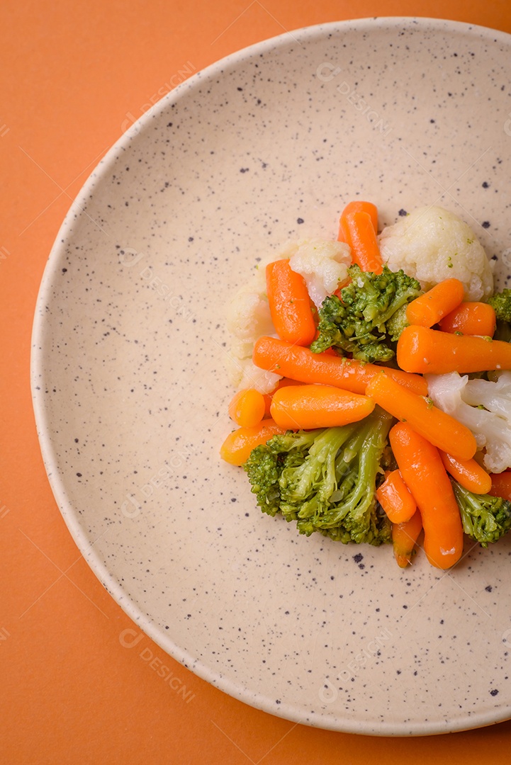 Deliciosos legumes frescos, brócolis, couve-flor, cenouras cozidas no vapor com sal, especiarias e ervas sobre fundo liso