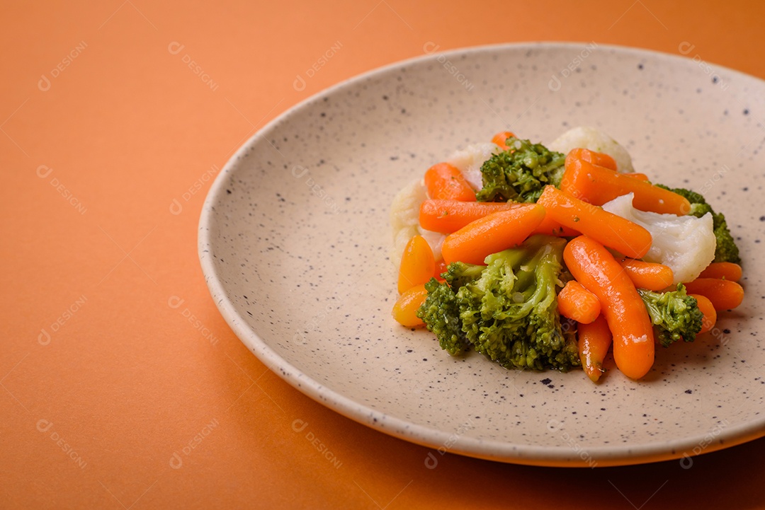 Deliciosos legumes frescos, brócolis, couve-flor, cenouras cozidas no vapor com sal, especiarias e ervas sobre fundo liso