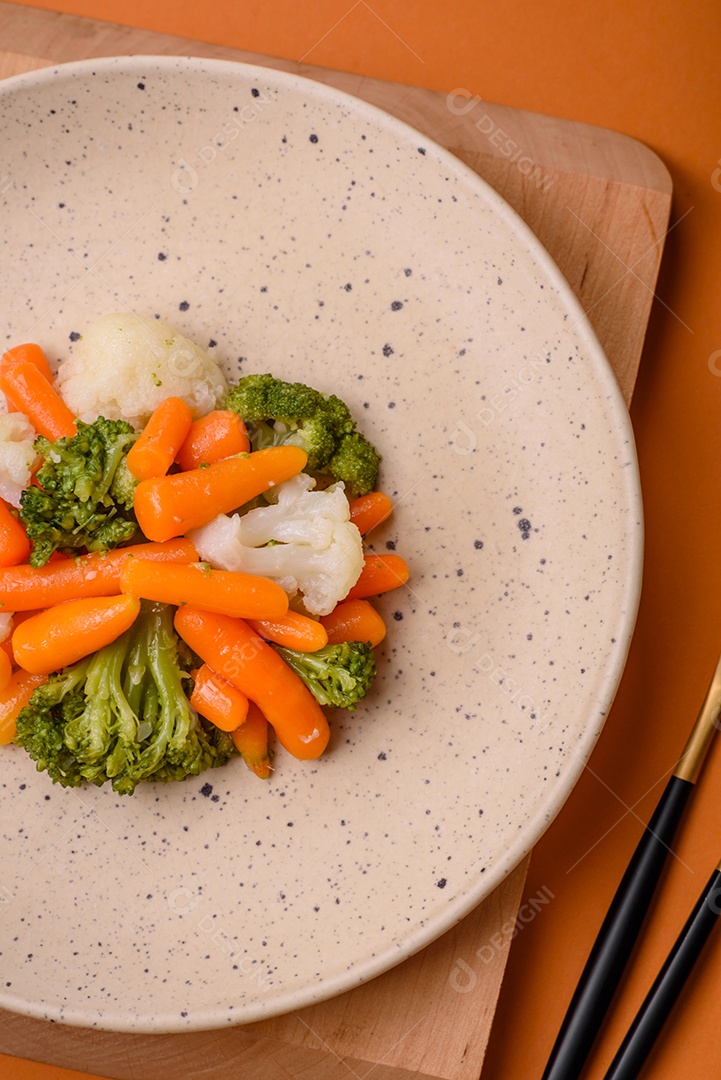 Deliciosos legumes frescos, brócolis, couve-flor, cenouras cozidas no vapor com sal, especiarias e ervas sobre fundo liso