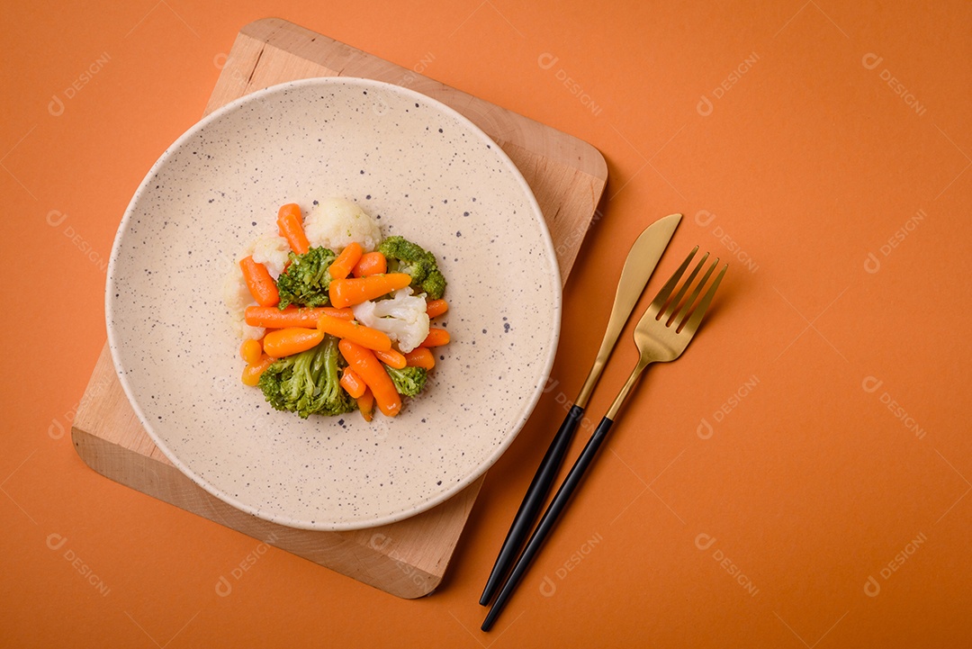 Deliciosos legumes frescos, brócolis, couve-flor, cenouras cozidas no vapor com sal, especiarias e ervas sobre fundo liso