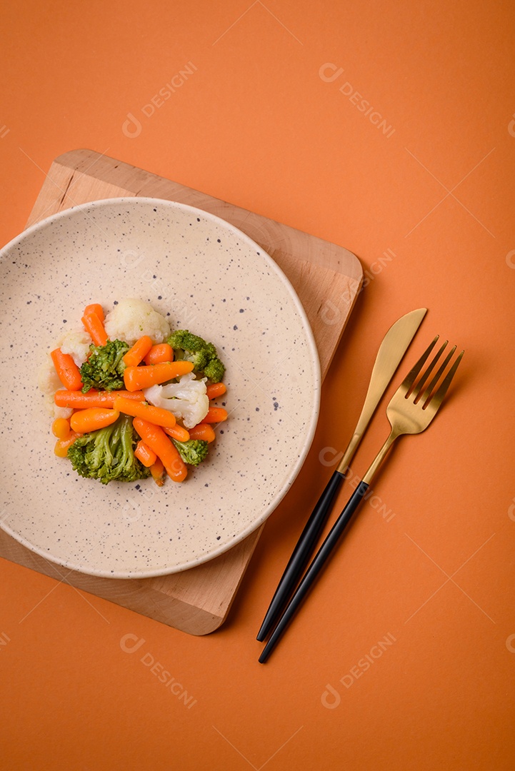 Deliciosos legumes frescos, brócolis, couve-flor, cenouras cozidas no vapor com sal, especiarias e ervas sobre fundo liso