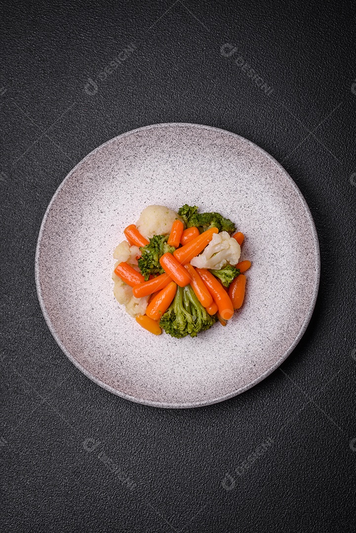 Deliciosos legumes frescos, brócolis, couve-flor, cenouras cozidas no vapor com sal, especiarias e ervas sobre fundo liso