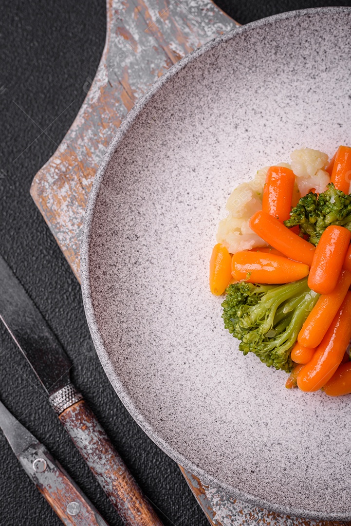 Deliciosos legumes frescos, brócolis, couve-flor, cenouras cozidas no vapor com sal, especiarias e ervas sobre fundo liso