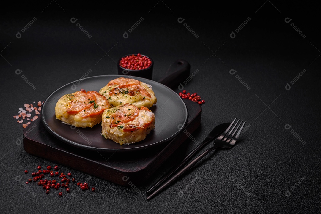 Delicioso filé de peixe assado com queijo, tomate, sal, especiarias e ervas sobre um fundo escuro de concreto