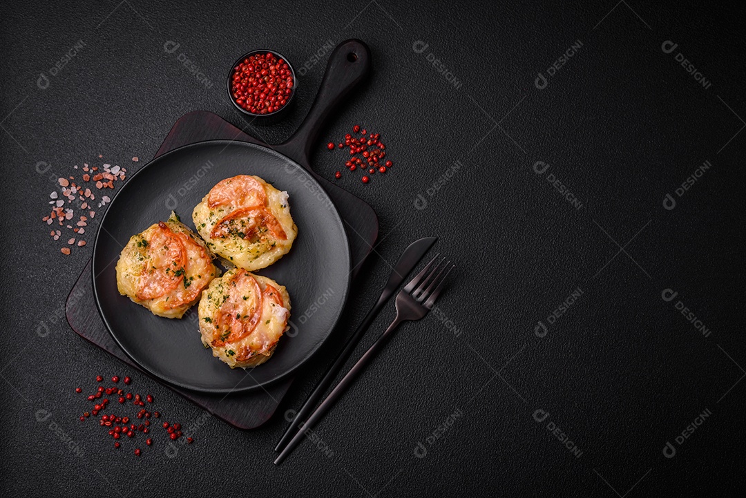 Delicioso filé de peixe assado com queijo, tomate, sal, especiarias e ervas sobre um fundo escuro de concreto