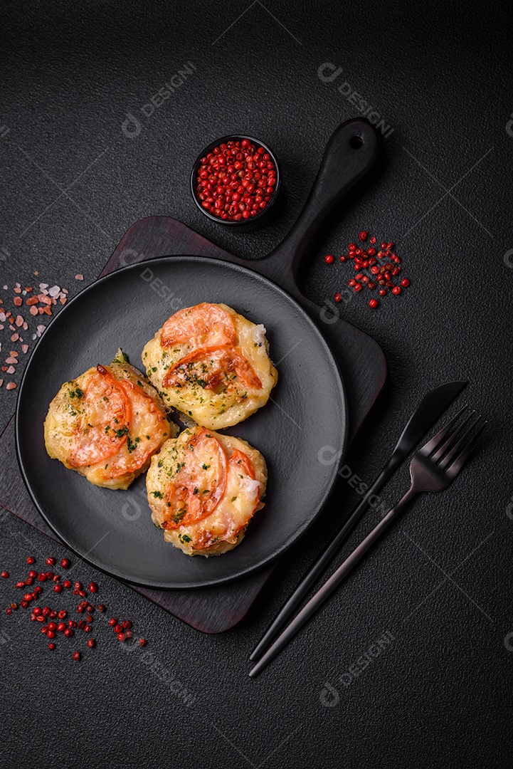 Delicioso filé de peixe assado com queijo, tomate, sal, especiarias e ervas sobre um fundo escuro de concreto