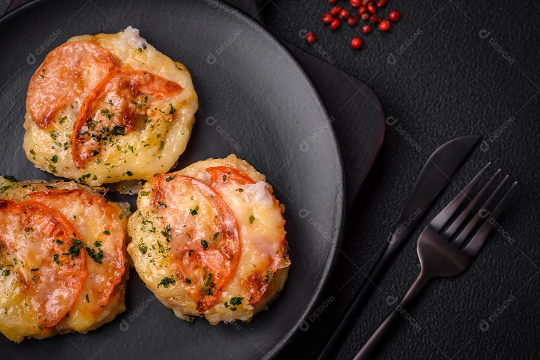 Delicioso filé de peixe assado com queijo, tomate, sal, especiarias e ervas sobre um fundo escuro de concreto