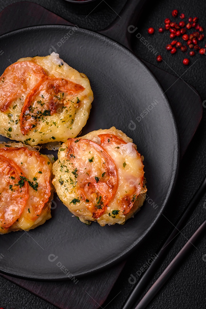 Delicioso filé de peixe assado com queijo, tomate, sal, especiarias e ervas sobre um fundo escuro de concreto
