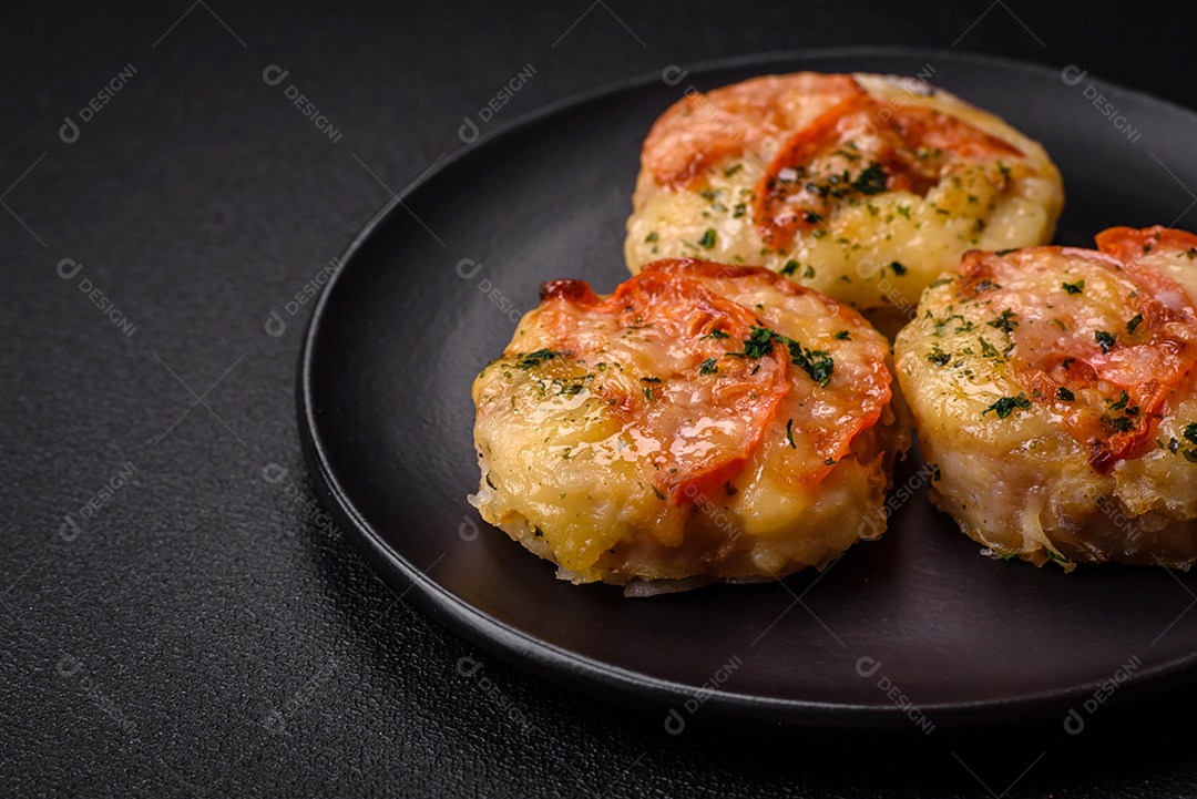 Delicioso filé de peixe assado com queijo, tomate, sal, especiarias e ervas sobre um fundo escuro de concreto