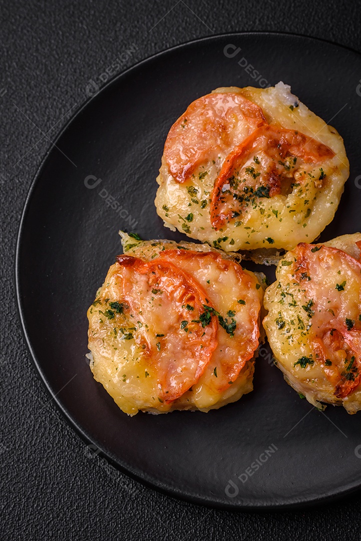 Delicioso filé de peixe assado com queijo, tomate, sal, especiarias e ervas sobre um fundo escuro de concreto