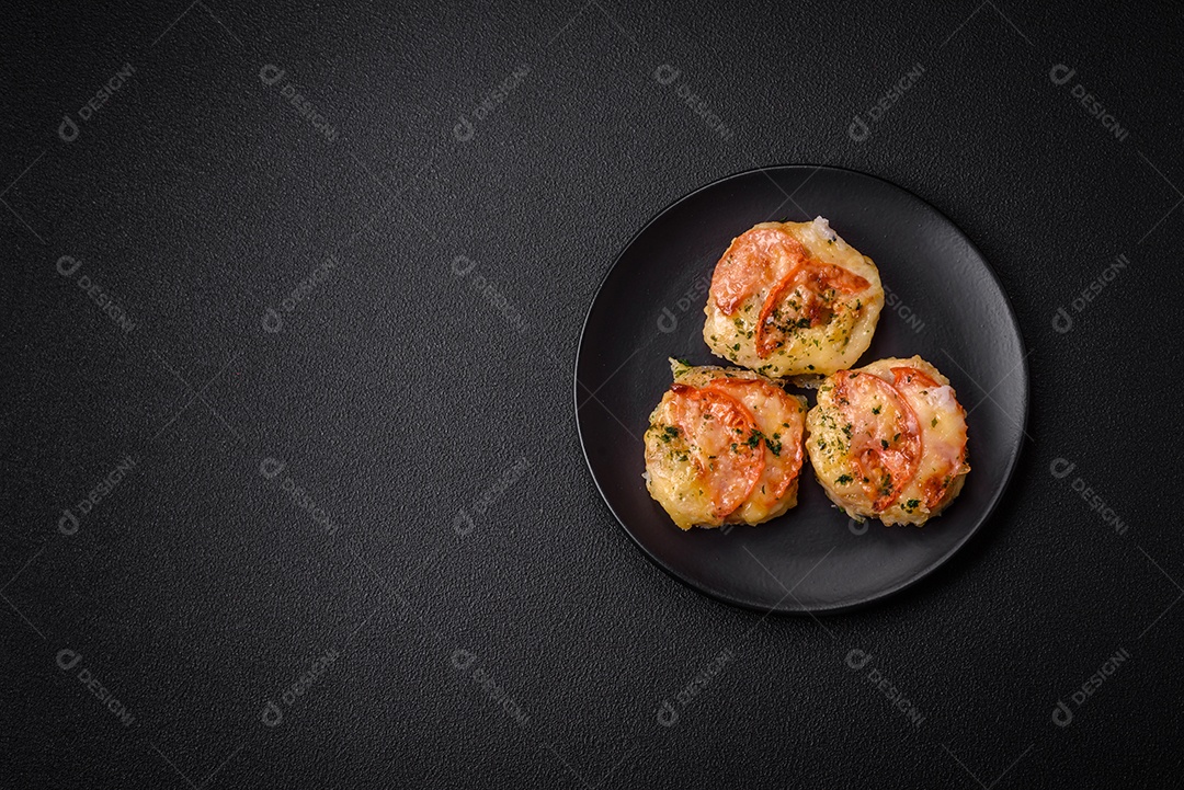 Delicioso filé de peixe assado com queijo, tomate, sal, especiarias e ervas sobre um fundo escuro de concreto