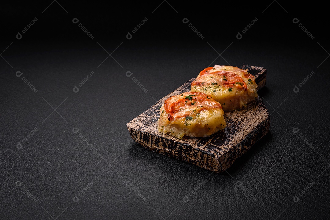 Delicioso filé de peixe assado com queijo, tomate, sal, especiarias e ervas sobre um fundo escuro de concreto