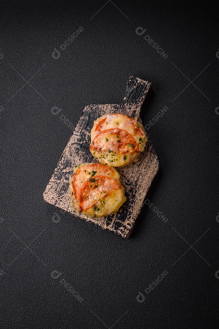 Delicioso filé de peixe assado com queijo, tomate, sal, especiarias e ervas sobre um fundo escuro de concreto
