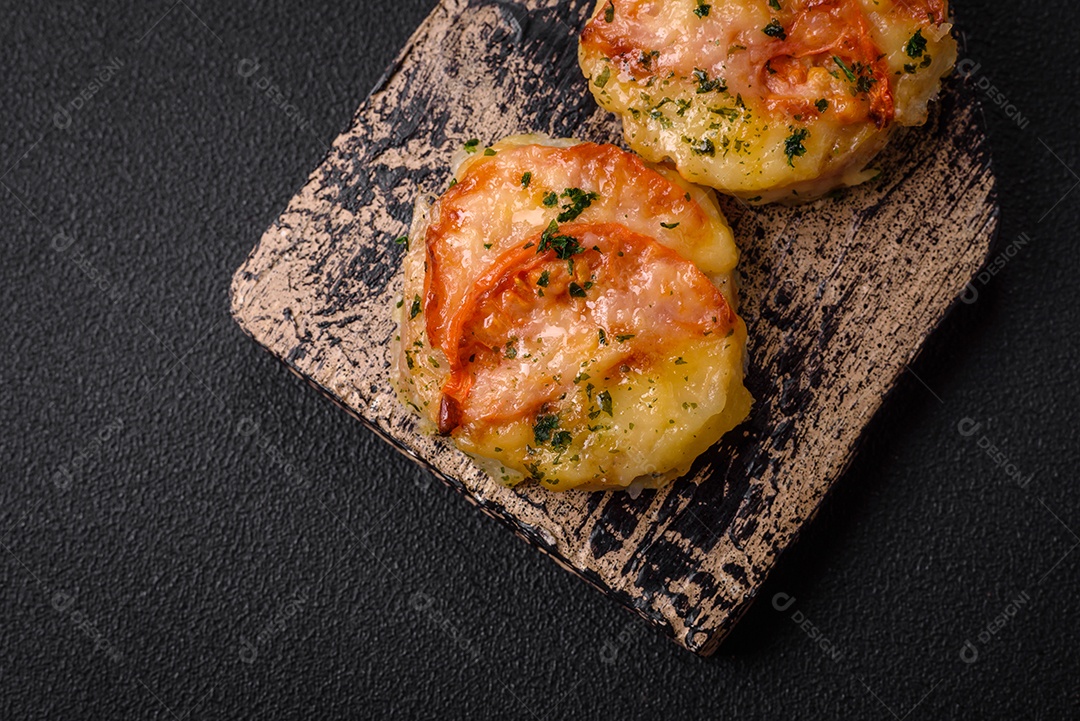 Delicioso filé de peixe assado com queijo, tomate, sal, especiarias e ervas sobre um fundo escuro de concreto