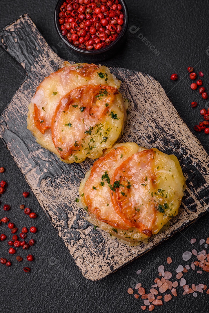 Delicioso filé de peixe assado com queijo, tomate, sal, especiarias e ervas sobre um fundo escuro de concreto