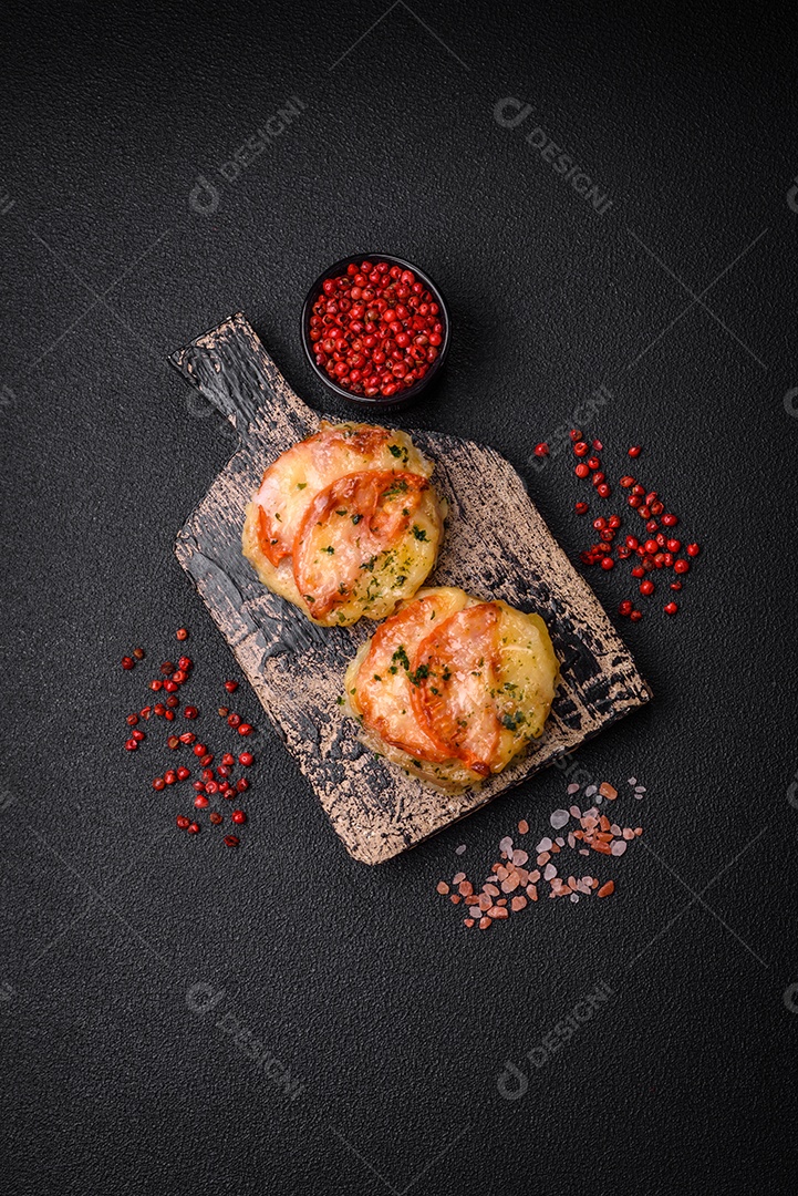 Delicioso filé de peixe assado com queijo, tomate, sal, especiarias e ervas sobre um fundo escuro de concreto