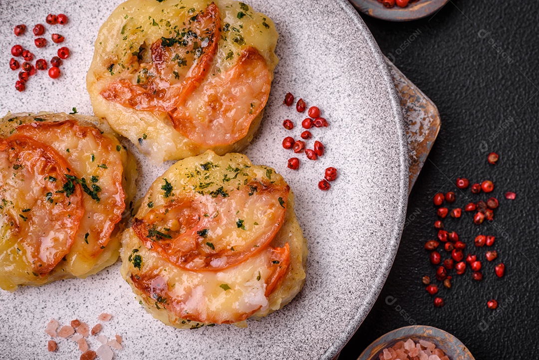 Delicioso filé de peixe assado com queijo, tomate, sal, especiarias e ervas sobre um fundo escuro de concreto