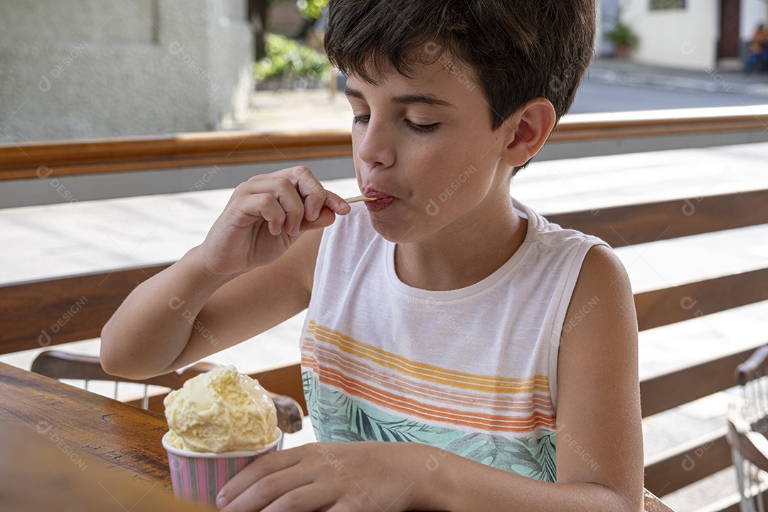 Criança brasileira de 10 anos tomando sorvete em tarde ensolarada.
