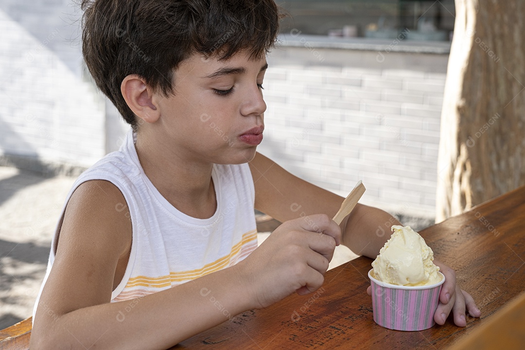 Criança brasileira de 10 anos tomando sorvete em tarde ensolarada.