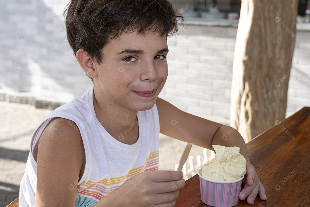 Criança brasileira de 10 anos tomando sorvete em tarde ensolarada.