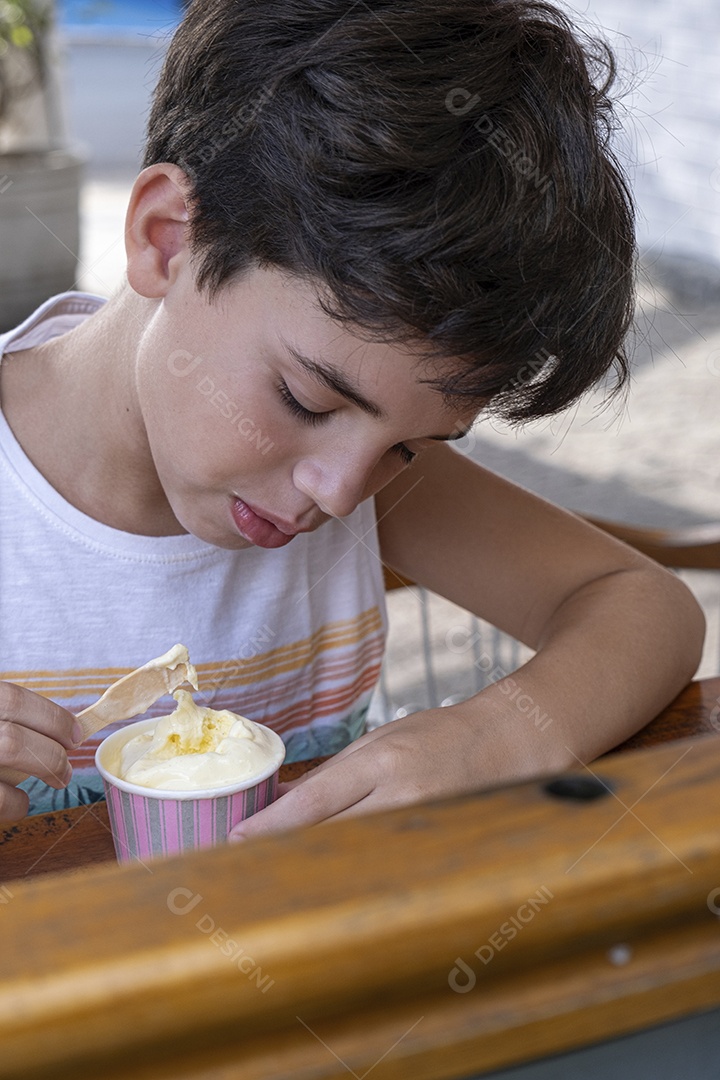 Criança brasileira de 10 anos tomando sorvete em tarde ensolarada.