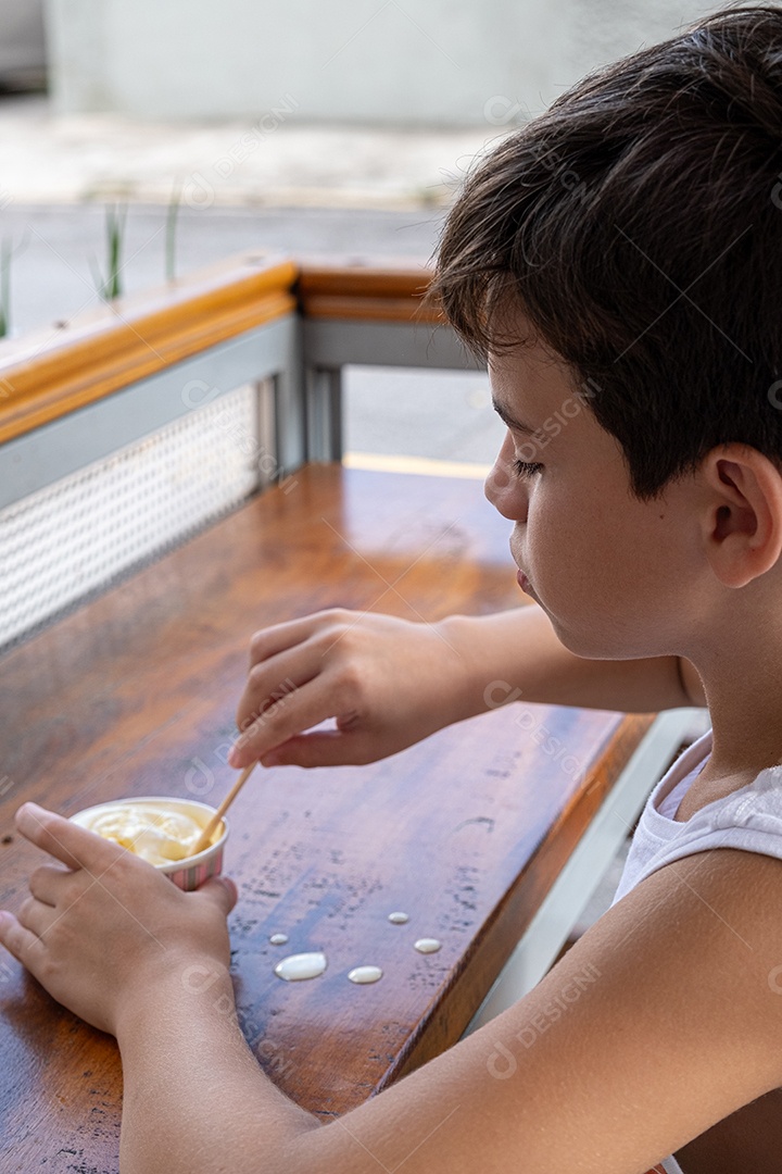 Criança brasileira de 10 anos tomando sorvete em tarde ensolarada.