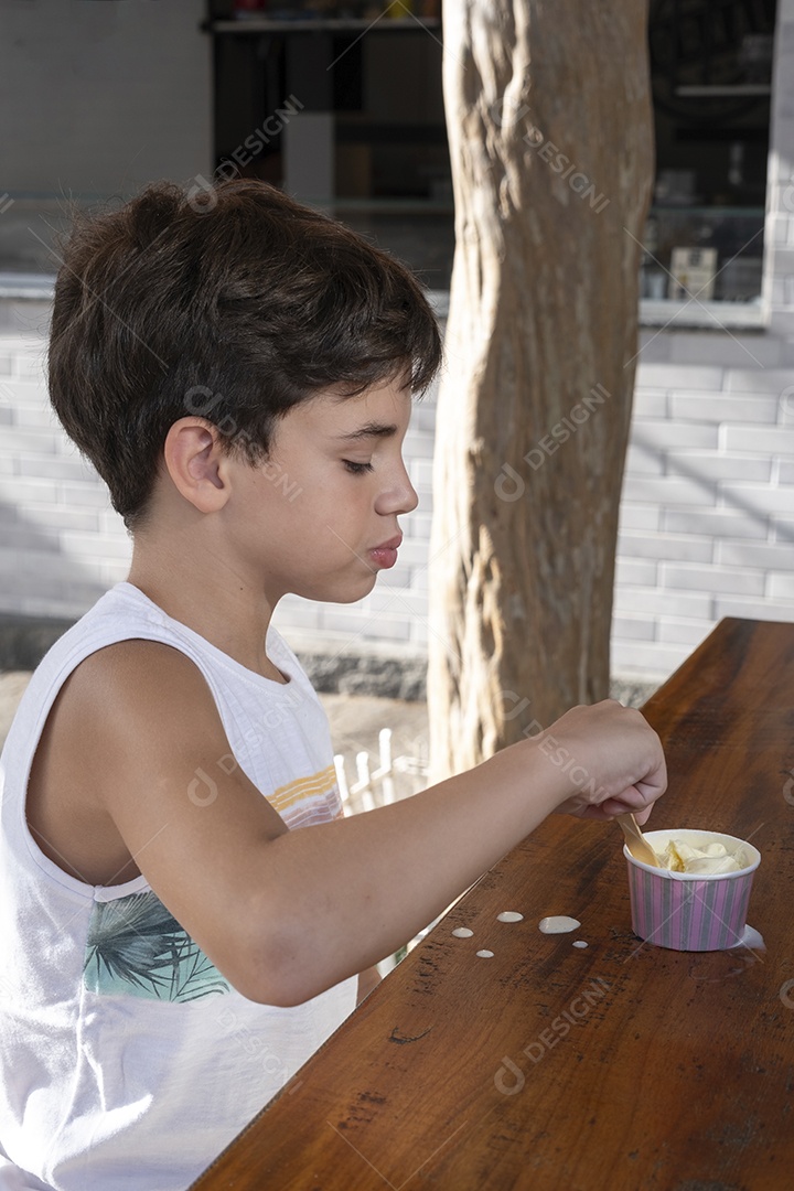 Criança brasileira de 10 anos tomando sorvete em tarde ensolarada.
