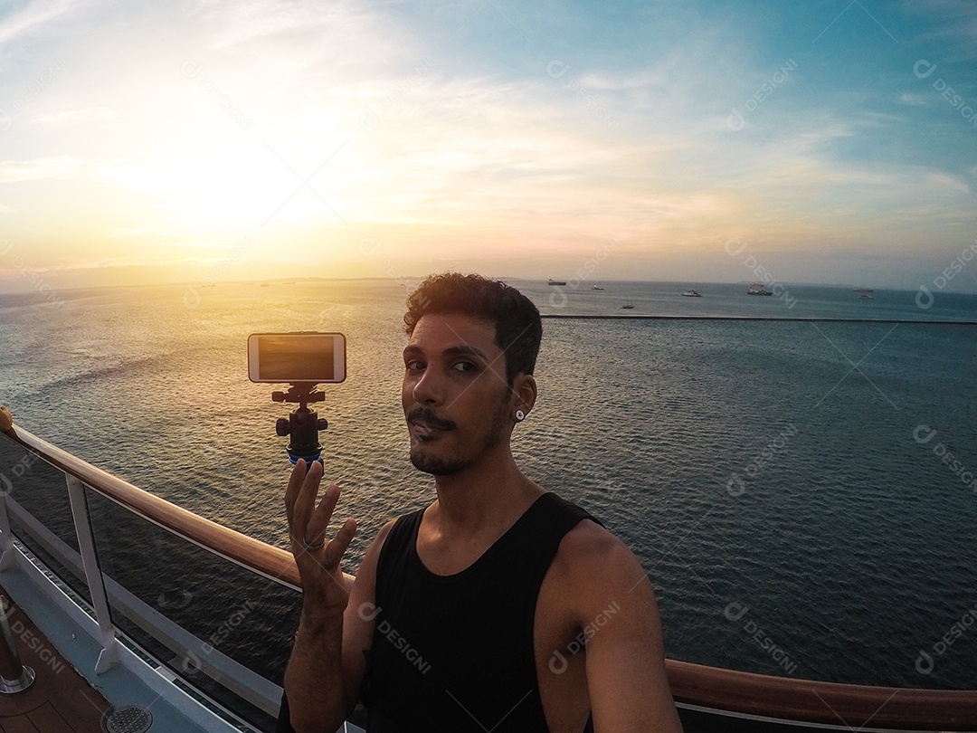 Retrato de um jovem turista negro no convés de um navio de cruzeiro em frente ao pôr do sol