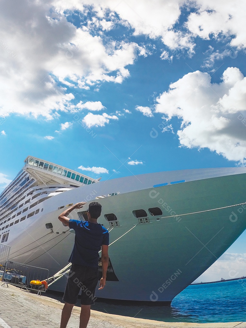 Retrato de um jovem turista negro em frente a um navio de cruzeiro em um céu nublado