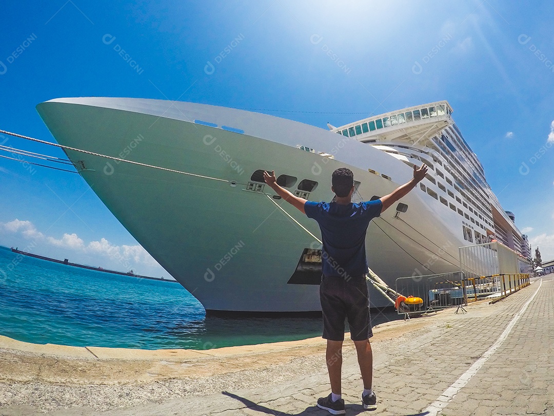 Retrato de um jovem turista negro em frente a um navio de cruzeiro em um céu nublado