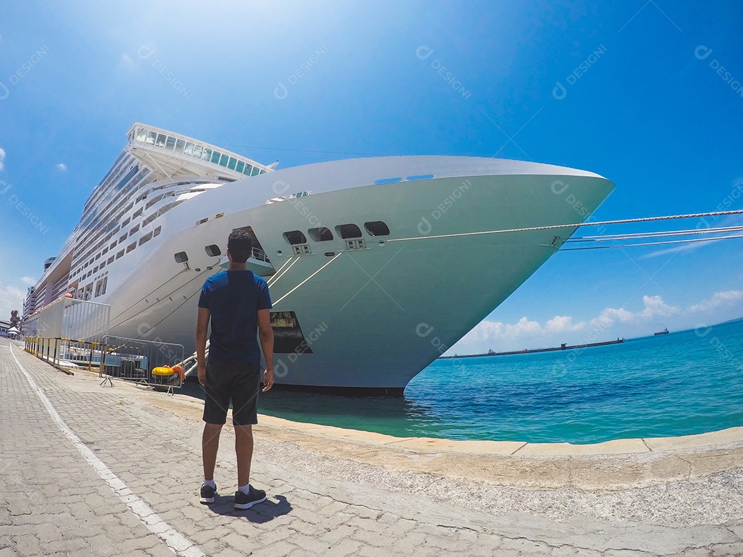 Retrato de um jovem turista negro em frente a um navio de cruzeiro em um céu nublado