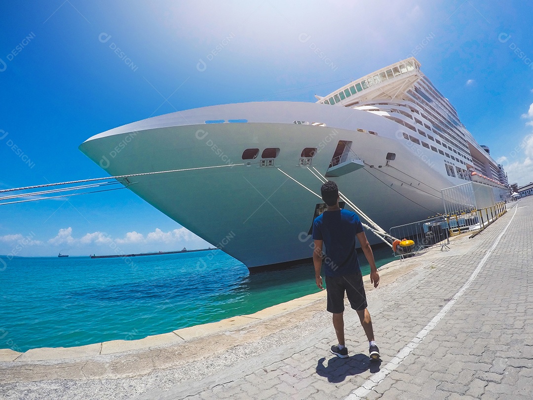 Retrato de um jovem turista negro em frente a um navio de cruzeiro em um céu nublado