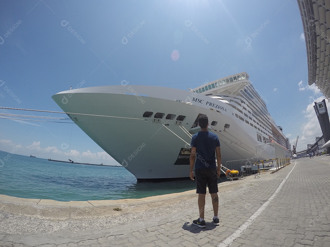 Retrato de um jovem turista negro em frente a um navio de cruzeiro em um céu nublado