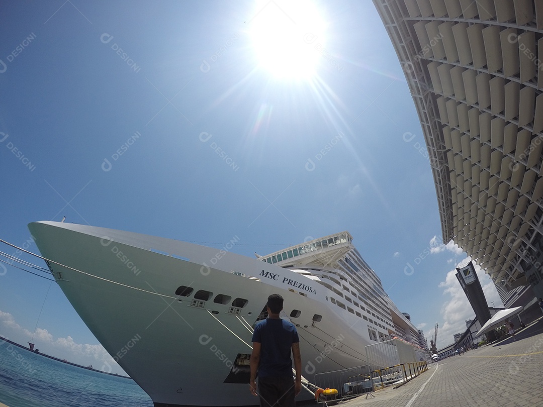 Retrato de um jovem turista negro em frente a um navio de cruzeiro em um céu nublado