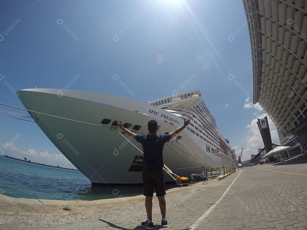 Retrato de um jovem turista negro em frente a um navio de cruzeiro em um céu nublado