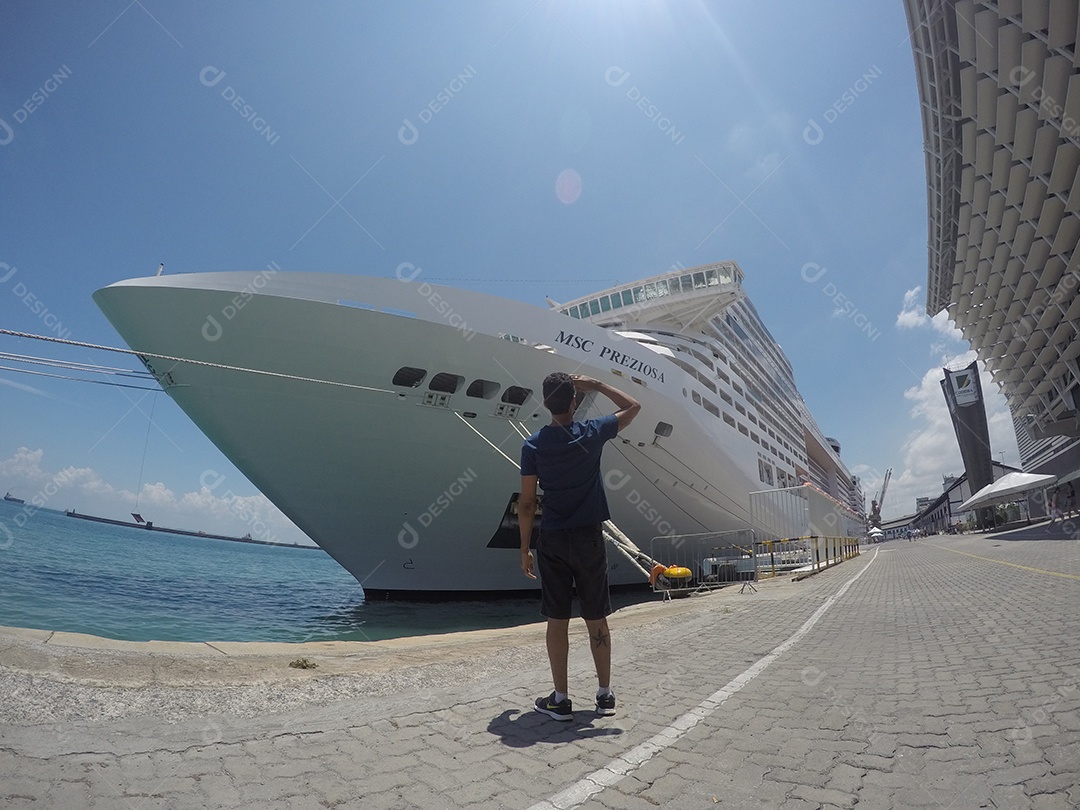 Retrato de um jovem turista negro em frente a um navio de cruzeiro em um céu nublado