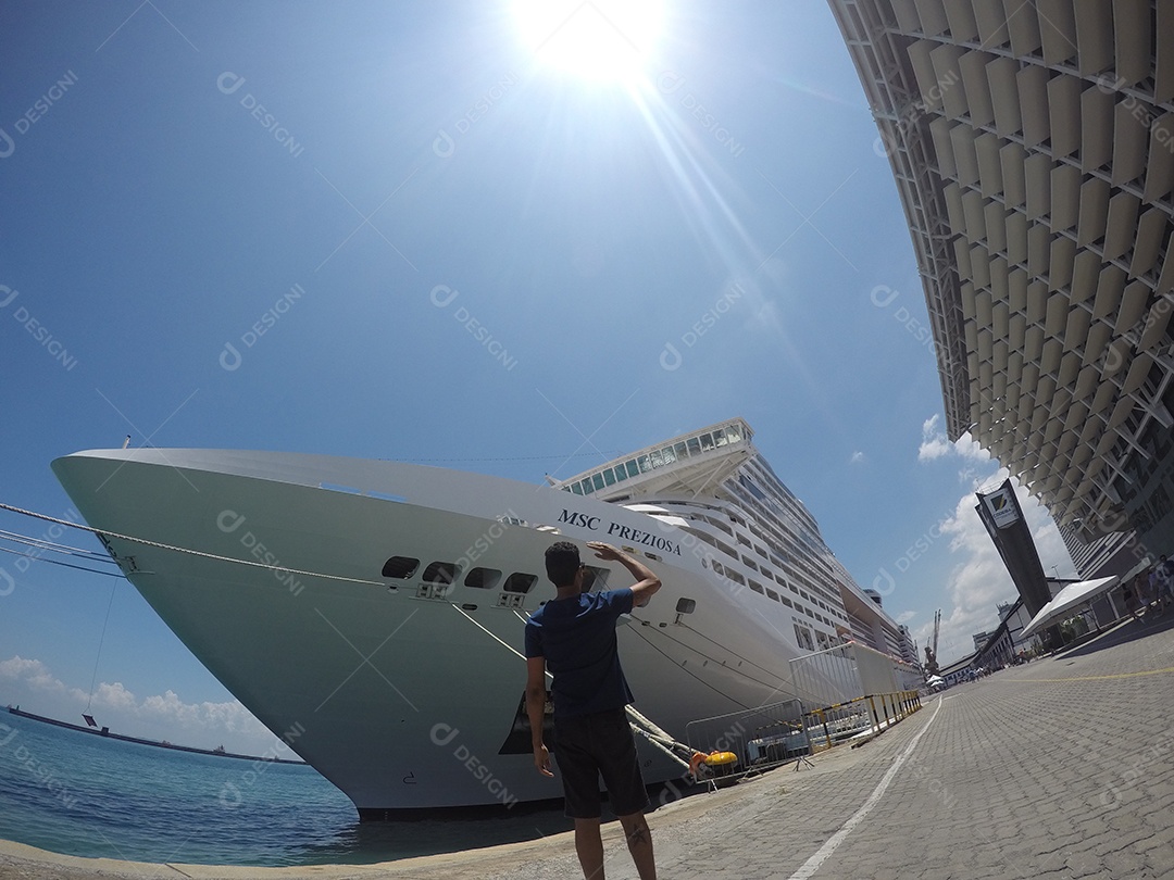Retrato de um jovem turista negro em frente a um navio de cruzeiro em um céu nublado
